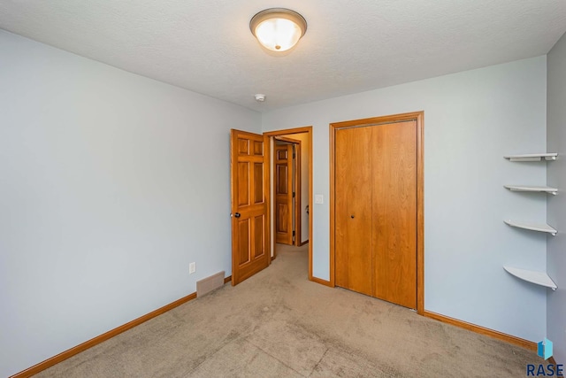 unfurnished bedroom with a textured ceiling, light colored carpet, and a closet