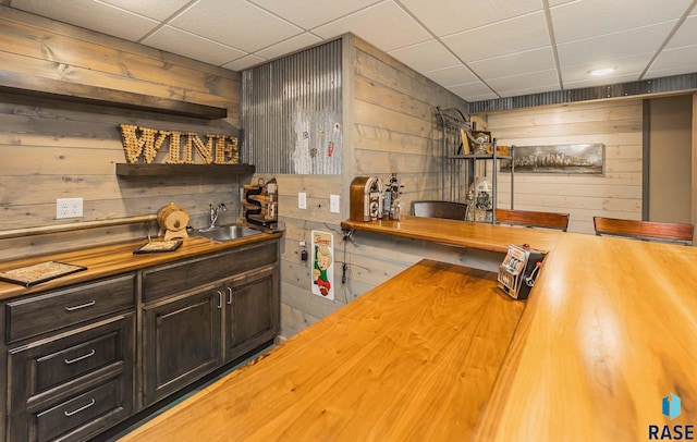 bar with wooden counters, dark brown cabinets, and wooden walls