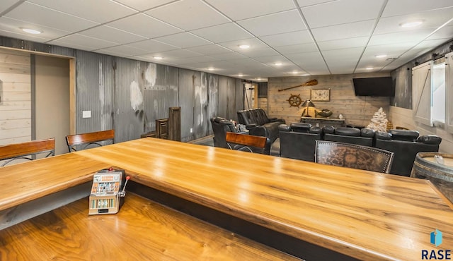 interior space featuring a barn door, wood walls, hardwood / wood-style flooring, and a paneled ceiling