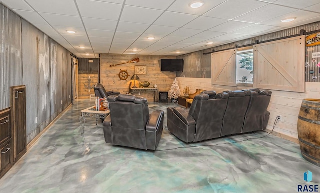 living room with concrete floors, a barn door, and wooden walls