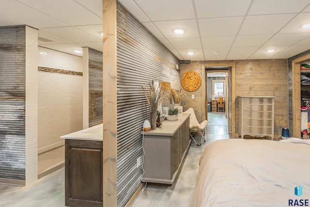 bedroom with concrete flooring and a paneled ceiling