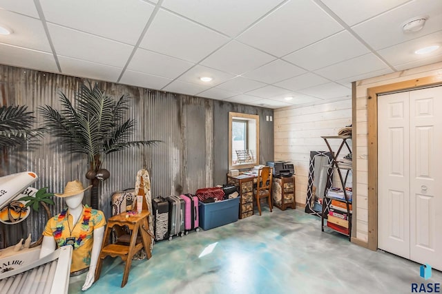 basement featuring a paneled ceiling and wood walls