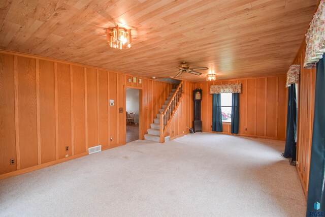 carpeted spare room featuring wood ceiling, ceiling fan, and wooden walls