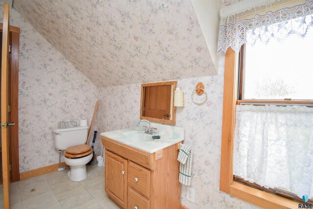 bathroom with tile patterned flooring, vanity, toilet, and vaulted ceiling