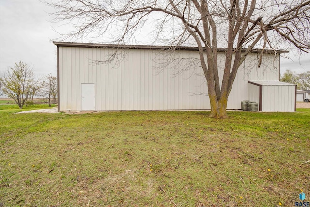 view of home's exterior featuring cooling unit, an outbuilding, and a yard