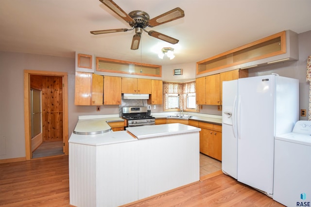 kitchen featuring light hardwood / wood-style flooring, stainless steel gas range oven, white fridge with ice dispenser, and washer / clothes dryer