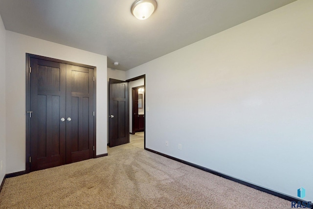 unfurnished bedroom with a closet and light colored carpet