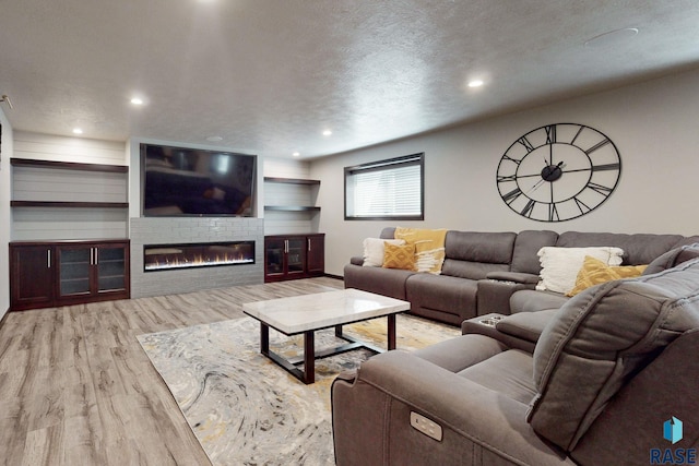 living room with a large fireplace, hardwood / wood-style floors, and a textured ceiling