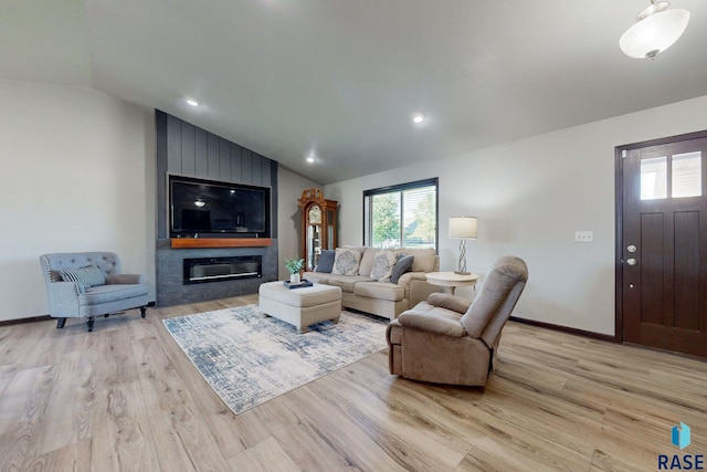 living room with lofted ceiling, a large fireplace, and light wood-type flooring