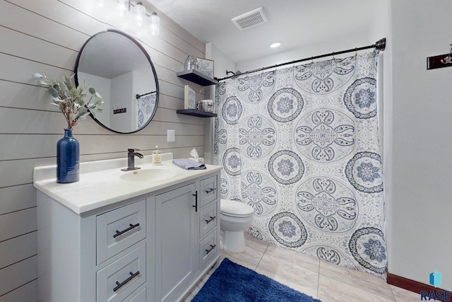 bathroom featuring vanity, walk in shower, toilet, tile patterned floors, and wooden walls