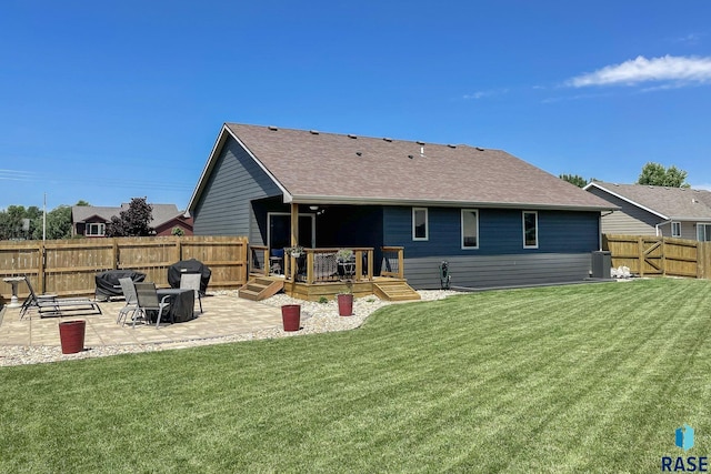 rear view of property with a yard, a wooden deck, and a patio