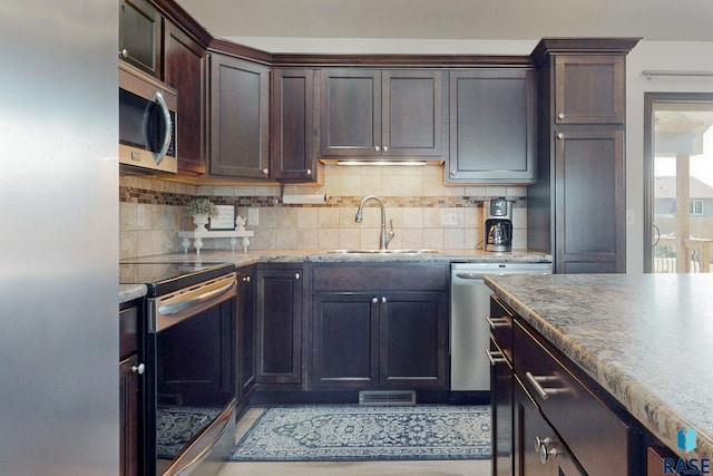 kitchen featuring appliances with stainless steel finishes, dark brown cabinets, backsplash, and sink