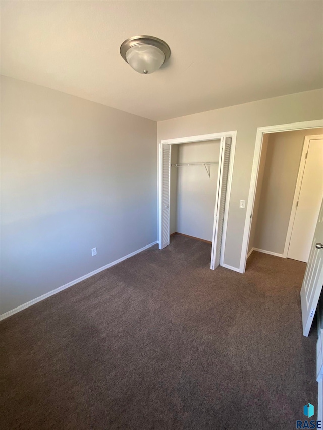 unfurnished bedroom with dark colored carpet and a closet