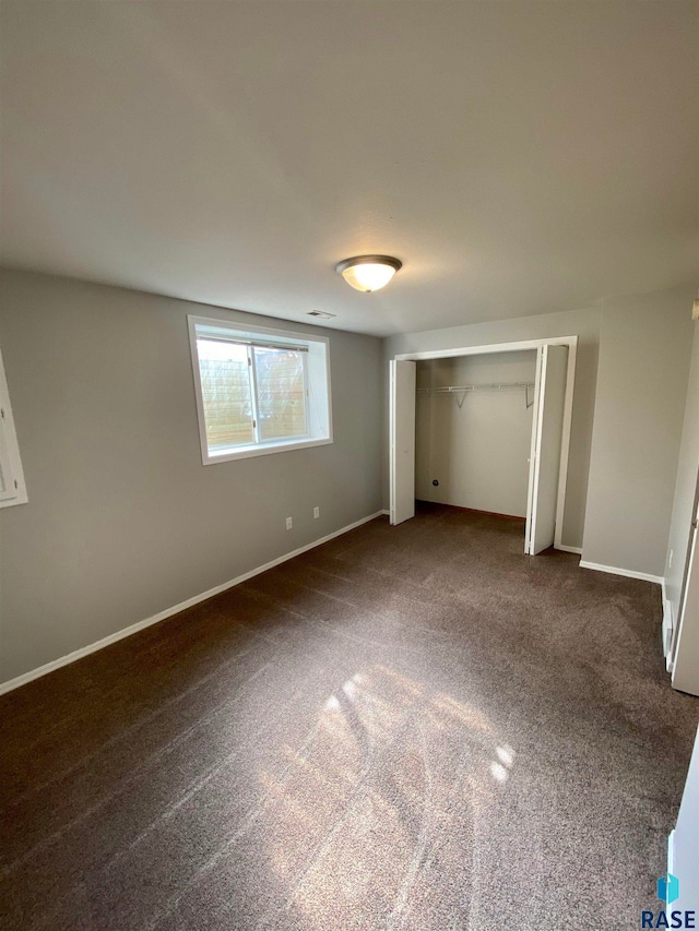 unfurnished bedroom featuring dark colored carpet and a closet