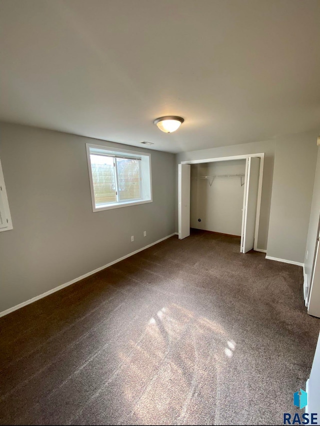 unfurnished bedroom with a closet and dark carpet