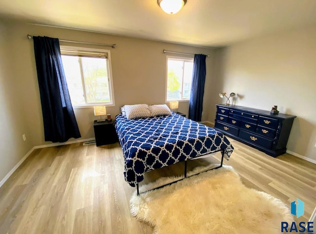 bedroom with light hardwood / wood-style floors and multiple windows