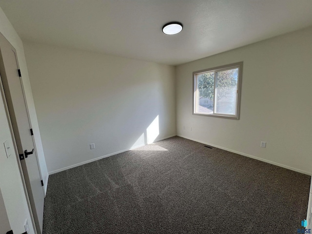 unfurnished room featuring dark carpet