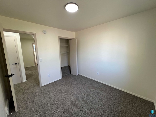 unfurnished bedroom with dark colored carpet and a closet