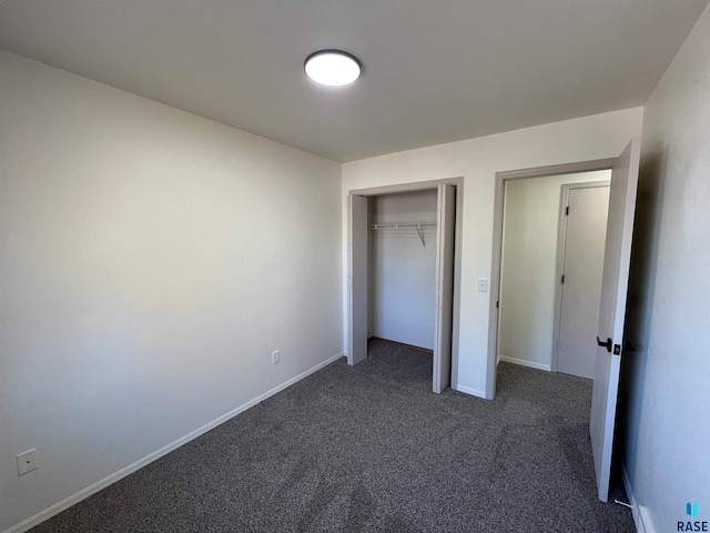 unfurnished bedroom with a closet and dark carpet