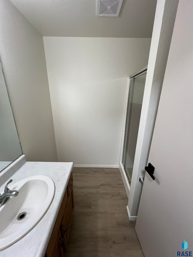 bathroom with an enclosed shower, wood-type flooring, and vanity