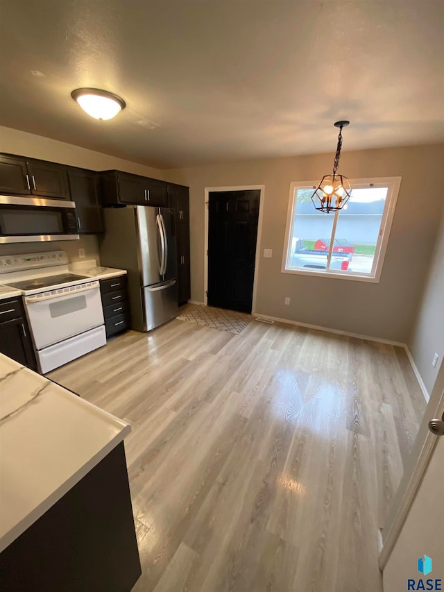 kitchen with light wood-type flooring, decorative light fixtures, appliances with stainless steel finishes, and a notable chandelier