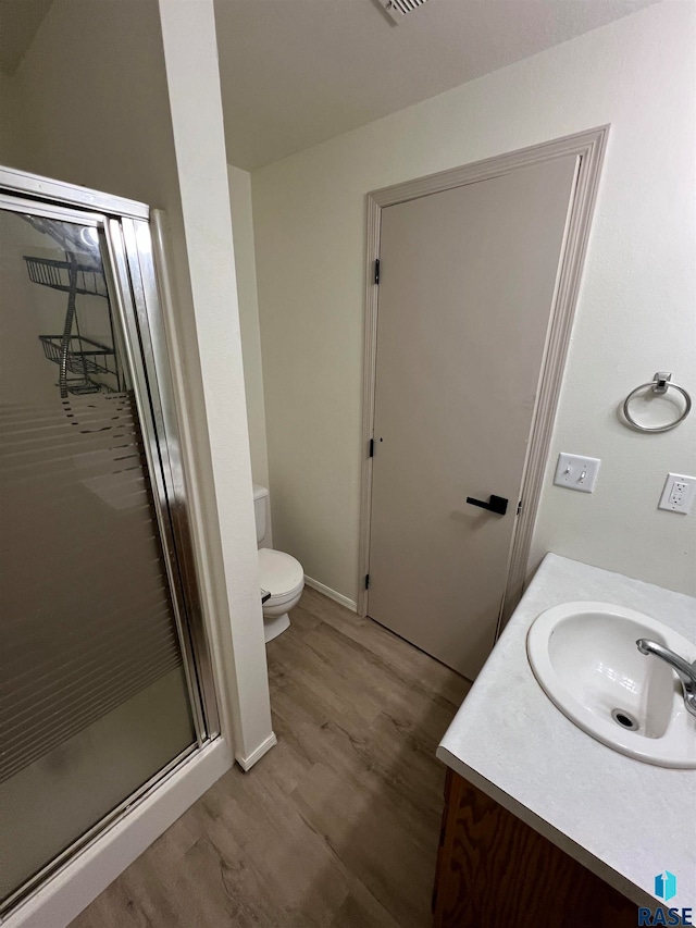 bathroom featuring toilet, vanity, hardwood / wood-style floors, and a shower with shower door