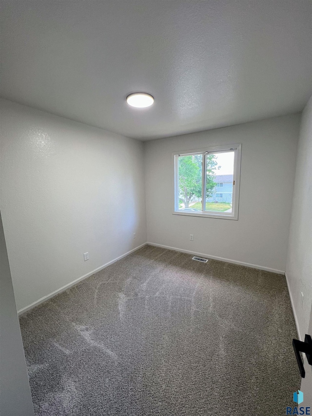 carpeted spare room with a textured ceiling