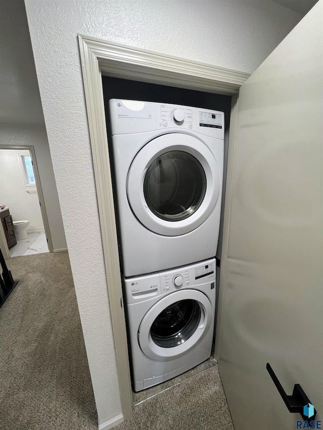 laundry area featuring light carpet and stacked washer / drying machine