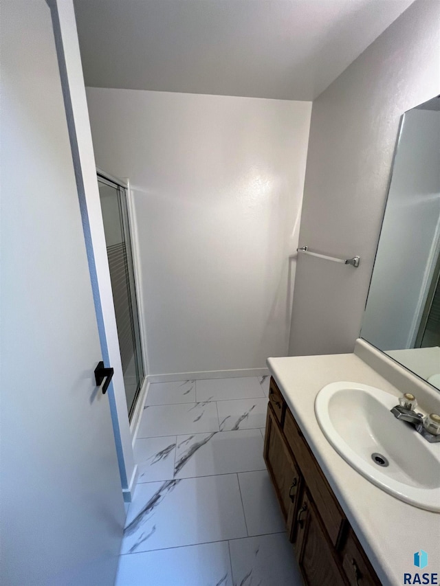 bathroom featuring a shower with shower door and vanity