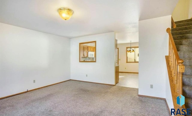 carpeted spare room featuring a chandelier