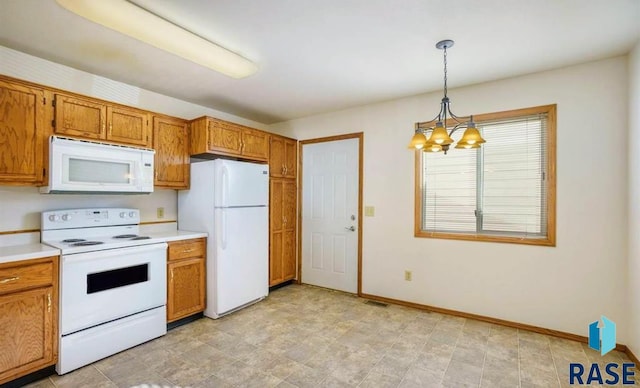 kitchen featuring white appliances, hanging light fixtures, and an inviting chandelier