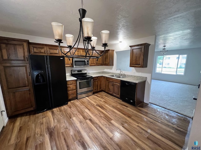 kitchen featuring black appliances, a textured ceiling, a notable chandelier, and sink