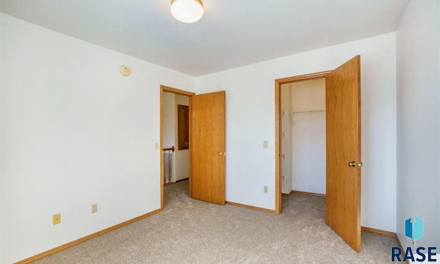 unfurnished bedroom with a closet, a walk in closet, and light carpet