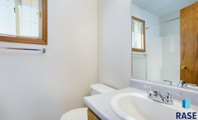 bathroom featuring walk in shower, toilet, and vanity