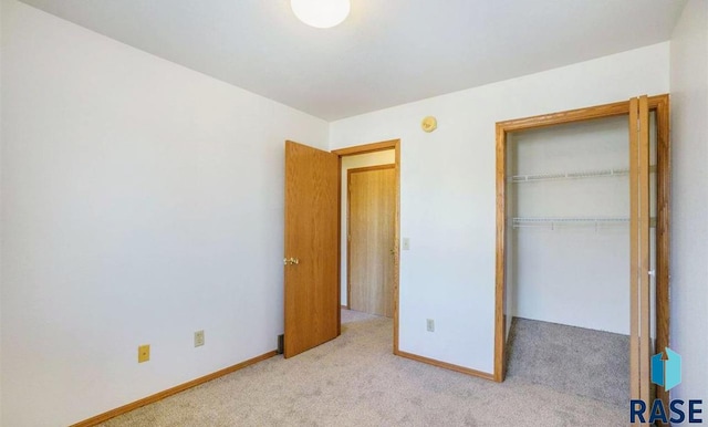 unfurnished bedroom with light carpet and a closet