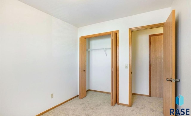 unfurnished bedroom featuring light colored carpet and a closet