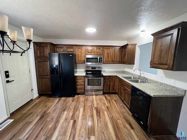 kitchen featuring light hardwood / wood-style flooring, black appliances, a chandelier, and sink