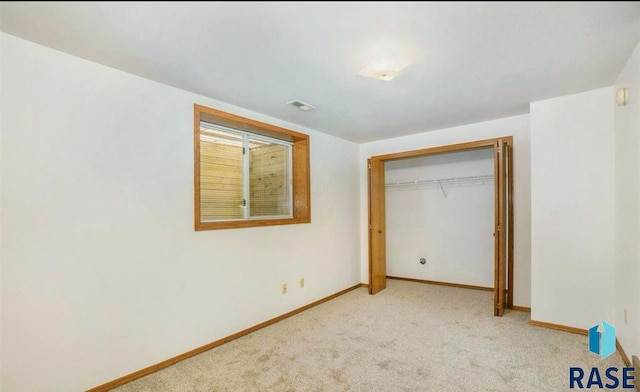 unfurnished bedroom with a closet and light carpet