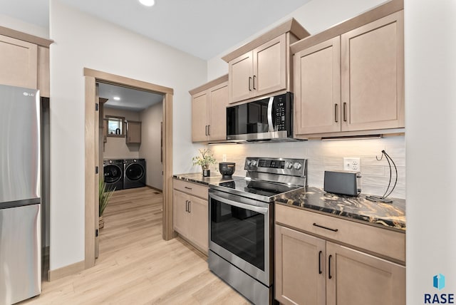 kitchen with appliances with stainless steel finishes, light brown cabinetry, light hardwood / wood-style flooring, and washer and clothes dryer