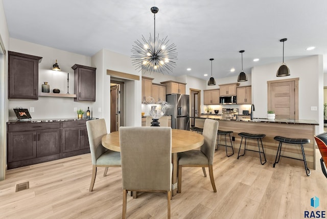 dining area featuring light hardwood / wood-style flooring, a notable chandelier, and sink