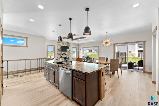 kitchen featuring an island with sink, light hardwood / wood-style flooring, stainless steel dishwasher, and sink