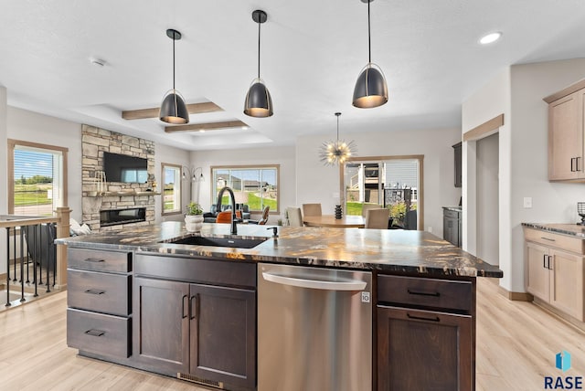 kitchen featuring dishwasher, light wood-type flooring, a wealth of natural light, and an island with sink