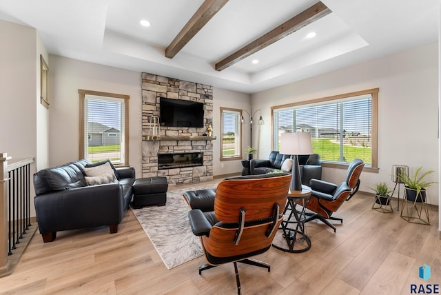 living room featuring a wealth of natural light, light wood-type flooring, beam ceiling, and a fireplace