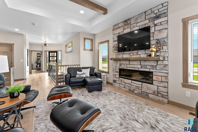 living room with light hardwood / wood-style floors, a healthy amount of sunlight, and a stone fireplace