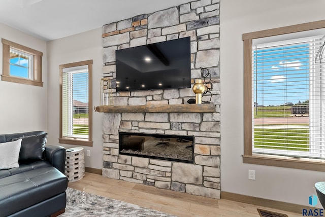 living room featuring a fireplace, light hardwood / wood-style floors, and a healthy amount of sunlight