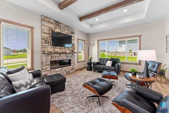 living room with light wood-type flooring, beam ceiling, and a stone fireplace