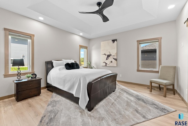 bedroom with a tray ceiling, light hardwood / wood-style flooring, and ceiling fan