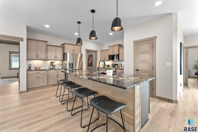 kitchen featuring appliances with stainless steel finishes, a kitchen breakfast bar, light hardwood / wood-style floors, and a kitchen island with sink