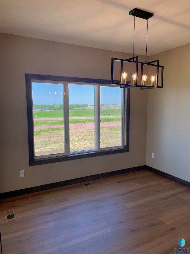 spare room featuring hardwood / wood-style floors and an inviting chandelier