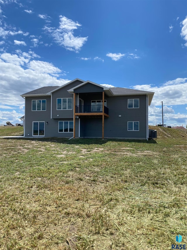 back of property with a balcony, a yard, and central AC